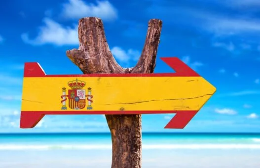Træskilt der viser spaniens flag og pilen peger på vidunderlige rejser til Spanien